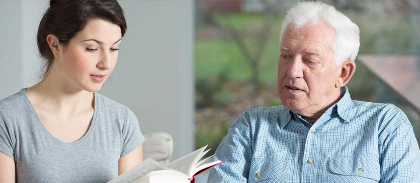 Woman Reading to Elderly Patient