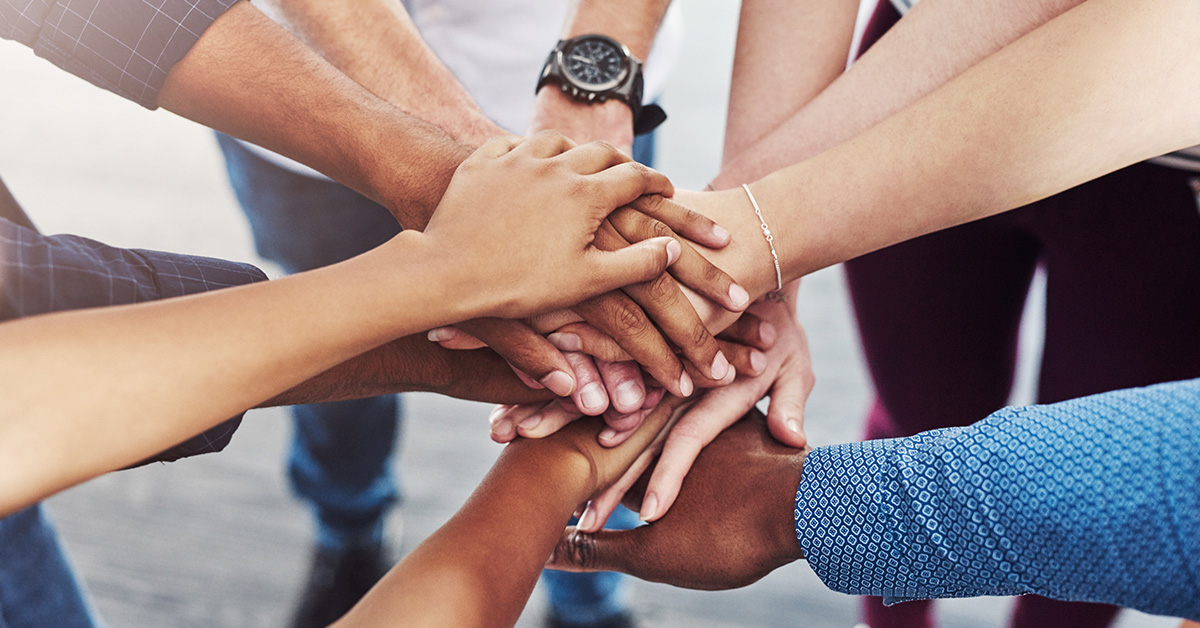 Hands of a diverse group of people coming together in teamwork